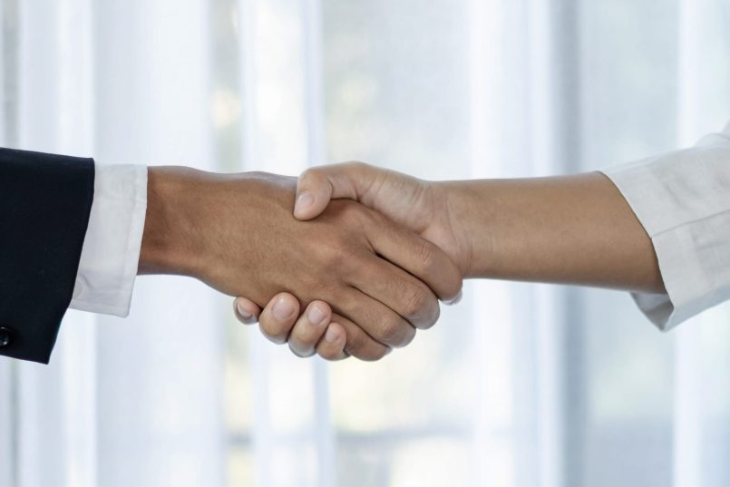 Two people shaking hands, representing partnership.